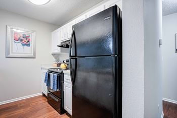 A black refrigerator in a kitchen with a picture on the wall